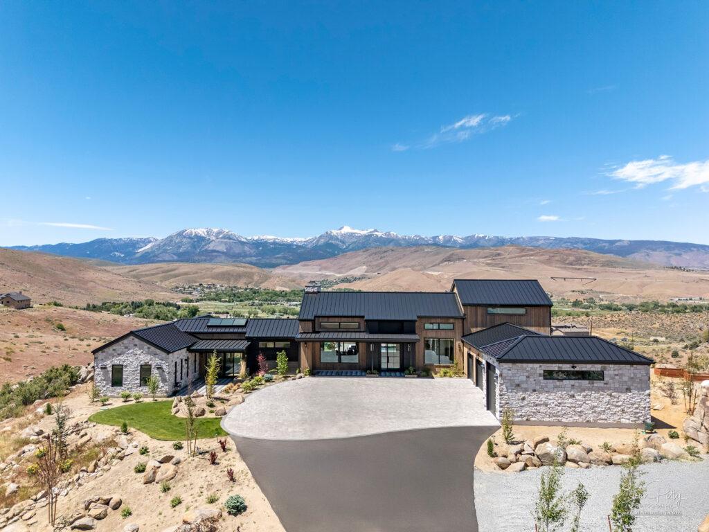 Drone view of luxury house with mountains behind.