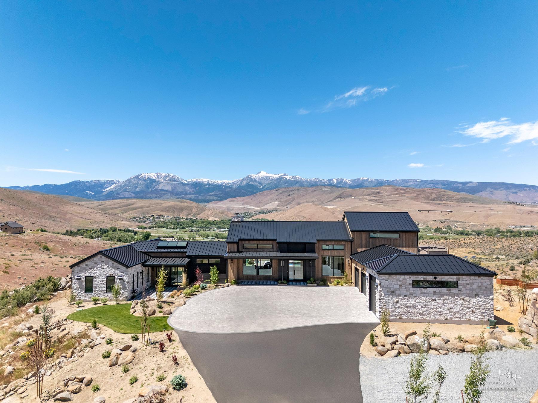 Drone view of luxury house with mountains behind.